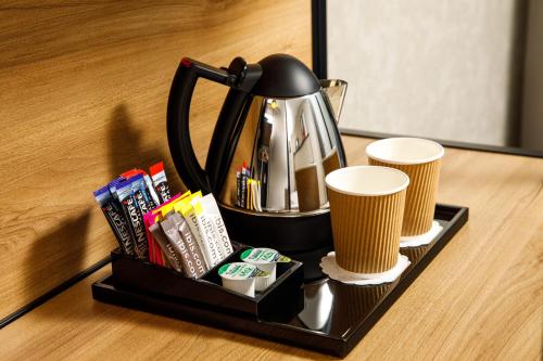 a tray with a tea kettle and two cups on a table at ibis London Sutton Point in Sutton