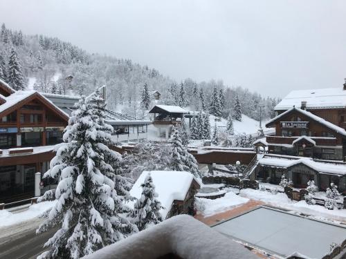 a snow covered tree in front of a lodge at Le Tremplin in Méribel