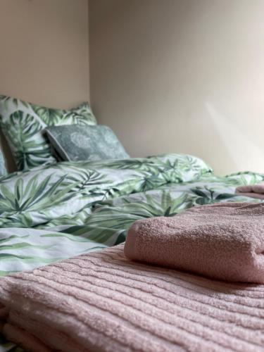 a bed with a green and white comforter with a pillow at Belle Apartaments in Międzyzdroje