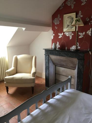 een slaapkamer met een stoel en een open haard bij L' Huis-au-Tilleul in Quarré-les-Tombes