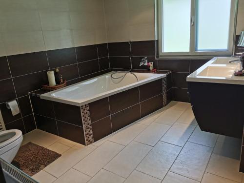 a bathroom with a tub and a toilet and a sink at Schwendi Maison in Mels