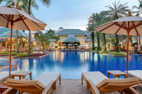 a pool at a resort with chairs and umbrellas at Holiday Inn Resort Phuket, an IHG Hotel in Patong Beach