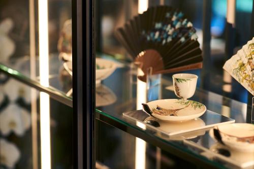 a glass display case with cups and saucers at Tassel Hotel Sanjo Shirakawa in Kyoto