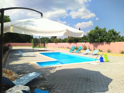 una piscina con sombrilla y sillas blancas y una piscina en Villa Konari, en Tolo