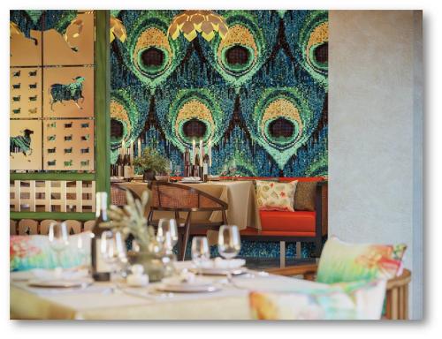 a restaurant with tables and chairs and a wall with a mural at Radisson Blu Resort Visakhapatnam in Visakhapatnam