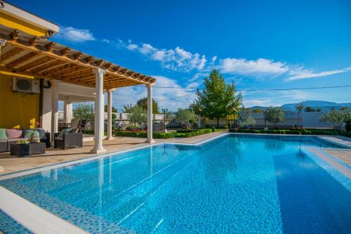 a swimming pool with a pergola next to a house at Holiday Home Petra in Donji Proložac