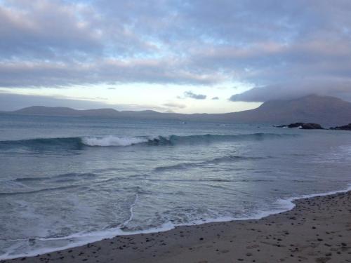 a beach with a wave in the ocean at Red Deer Cottage near Connemara National Park in Letterfrack in Letterfrack