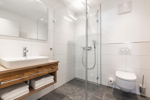 a bathroom with a shower and a sink and a toilet at Haus Fellhorn - Ferienwohnungen in Riezlern