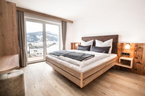 a bedroom with a large bed with a large window at Haus Fellhorn - Ferienwohnungen in Riezlern