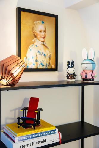 a shelf with a picture and a red chair and books at LOFT 188 Luxury Apartment Hotel in Utrecht