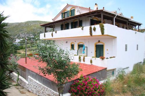 una casa blanca con techo rojo y flores en Evon's Rooms, en Fanari