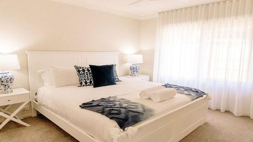 a bedroom with a white bed with two lamps and a window at McMillans of Metung Coastal Resort in Metung