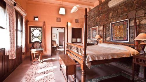 a bedroom with a bed and a stone wall at Neemrana Fort-Palace in Neemrana