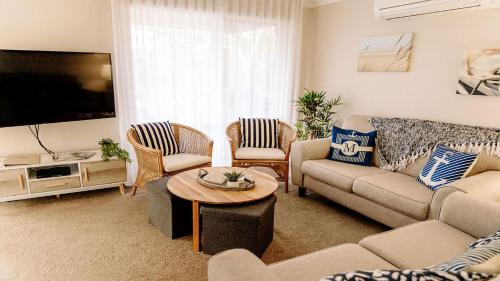 a living room with a couch and a tv at McMillans of Metung Coastal Resort in Metung