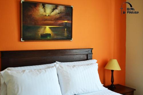 a bedroom with a painting above a bed with white pillows at Hotel La Plazuela in Popayan