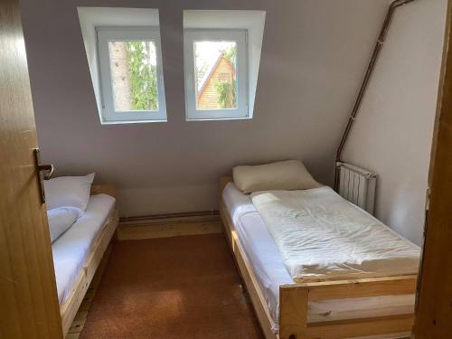 two beds in a small room with two windows at Vikendica ABASA Vlašić in Vlasic