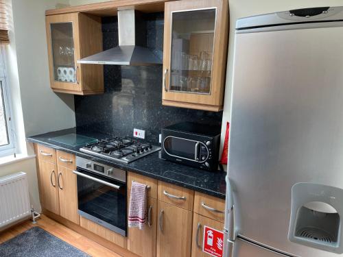 a kitchen with a stainless steel refrigerator and wooden cabinets at HARBOUR VIEW HOLIDAY LET - Entire 3 Bedroom Maisonette With Spectacular Harbour And Sea Front Views Sleeps 5 in Bridlington