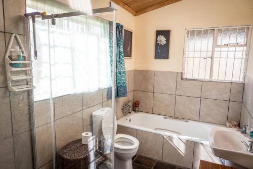 uma casa de banho com uma banheira, um WC e um lavatório. em Artists cottage em Ladybrand