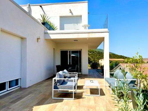 a patio with white furniture on a house at villa I Cresti proche centre ville et plages in Ajaccio