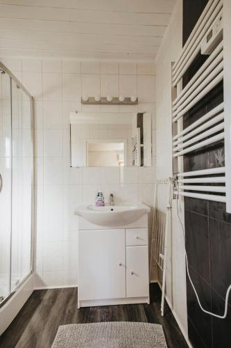a white bathroom with a sink and a refrigerator at Domki letniskowe Babie Doły in Gdynia