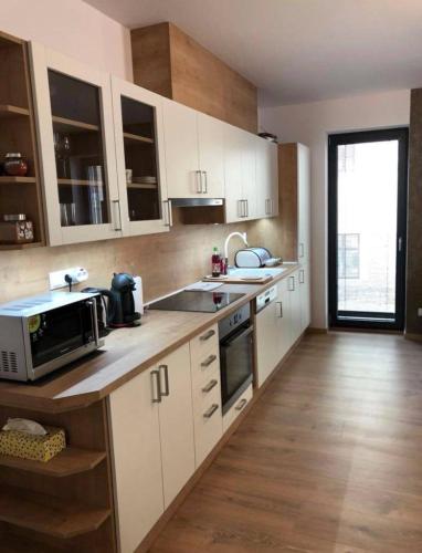 a kitchen with white cabinets and a sink and a microwave at Apartmán Osmička Vrchlabí in Vrchlabí