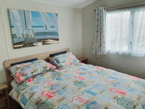 a bed with a quilt and pillows in a bedroom at Premium accommodation with luxury HOT-TUB and decking area, near Fantasy Island in Ingoldmells