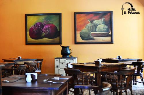 a restaurant with wooden tables and paintings on the wall at Hotel La Plazuela in Popayan