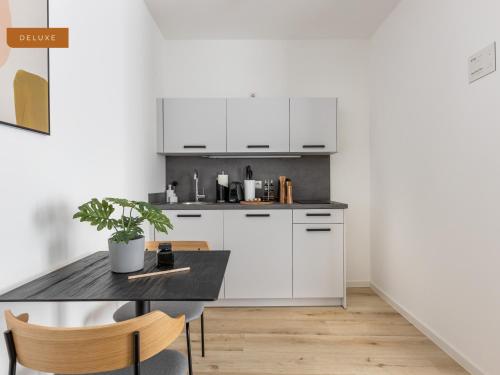 a kitchen with white cabinets and a table with a potted plant at limehome Osnabrück Johannisstraße in Osnabrück