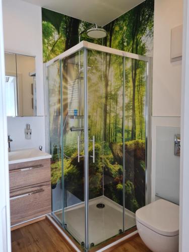 a bathroom with a shower with a forest mural on the wall at Ferienapartment Heimatgefühl in Bühl