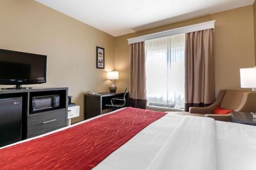 a hotel room with a bed and a flat screen tv at Comfort Inn & Suites Ponca City near Marland Mansion in Ponca City