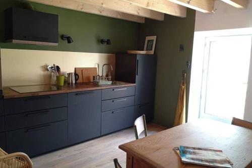 une cuisine avec des placards bleus et une table en bois dans l'établissement La Dilettante, petite maison rénovée, avec jardin, à Vertaizon