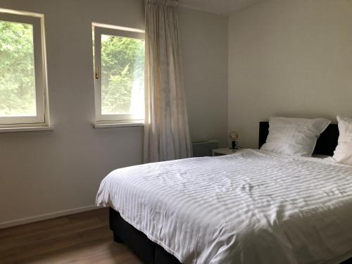 a bedroom with a white bed and two windows at B&B Het Zonnehuis Boxtel in Boxtel