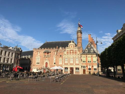 an old building with a clock tower and tables and chairs at De Haarlemse Logeerkamer in Haarlem