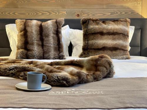 a faux fur blanket on a bed with a cup of coffee at Aspen Golf and Ski Resort in Bansko