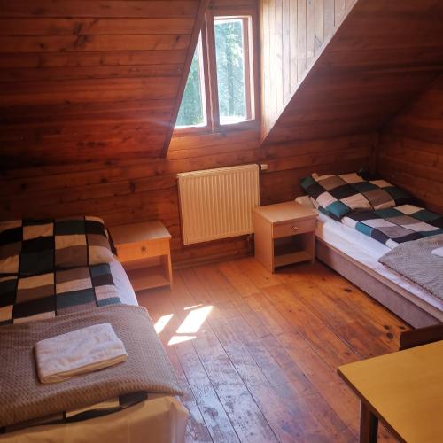 a room with two beds in a wooden cabin at SzSM Hadle Szklarskie in Hadle Szklarskie