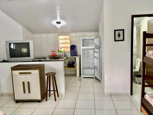 a kitchen with a refrigerator and a table and stool at Chalés Damata in Ubatuba