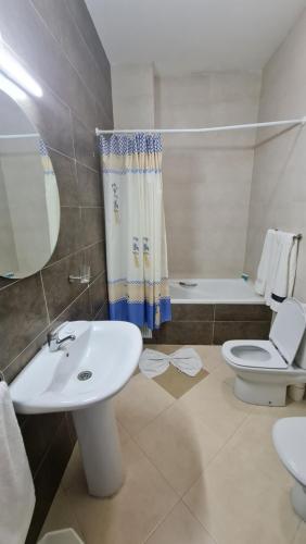 een badkamer met een wastafel, een toilet en een bad bij Hotel La Corniche Fnideq in Fnidek