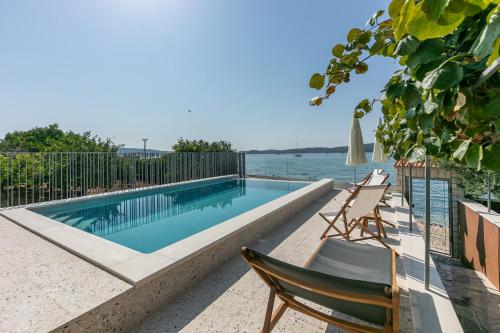 a swimming pool with two chairs next to the water at Apartments Sea in Trogir