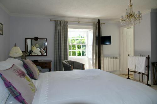 Un dormitorio con una gran cama blanca y una ventana en Thistleyhaugh farmhouse, en Longhorsley