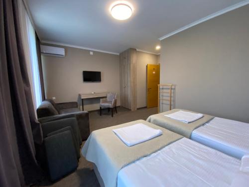 a hotel room with two beds and a chair and a desk at Ponte in Kutaisi