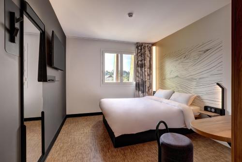 PublierにあるB&B HOTEL Evian Publierの大きなベッドとテーブルが備わるホテルルームです。