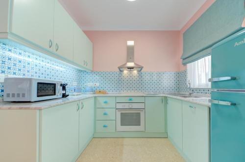 cocina con armarios azules y blancos y microondas en Colorful & Spacious Home with Yard - Close to Xemxija Bay, en St Paul's Bay
