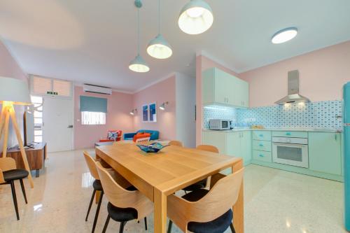 uma cozinha e sala de jantar com uma mesa de madeira e cadeiras em Colorful & Spacious Home with Yard - Close to Xemxija Bay em St Paul's Bay