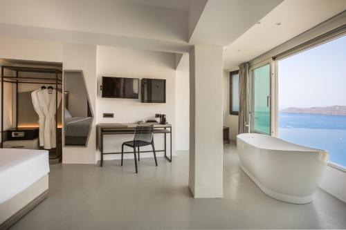 a bathroom with a tub and a desk with a view at Sun Rocks Boutique Hotel in Firostefani