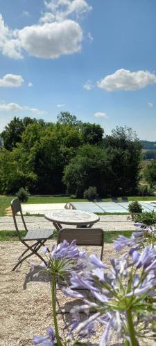 a patio with a table and chairs and purple flowers at Demeure de la Garenne in Montmirail