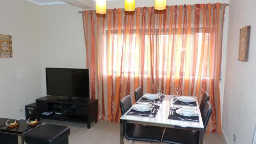 a dining room with a table with chairs and a television at My Sunny Apartment Barra in Praia da Barra