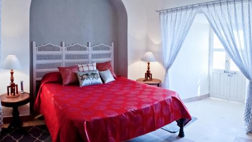 a bedroom with a red bed with a red comforter at Neemrana's - Tijara Fort Palace in Alwar