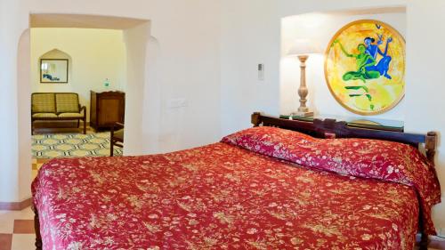 a bedroom with a bed with a red bedspread at Neemrana's - Tijara Fort Palace in Alwar