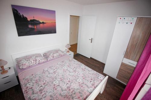 a small bedroom with a bed with a pink bedspread at Apartman Mirno More in Selce
