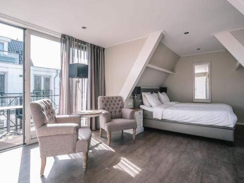 een hotelkamer met een bed en twee stoelen bij Juuls Domburg in Domburg
